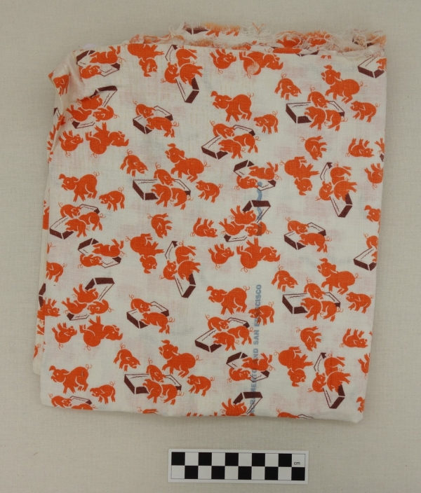 Length of cotton cloth with a design of orange pigs of various sizes eating at brown troughs. USA, mid-1950&#039;s (TRC 2017.1366).