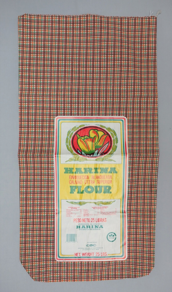 Large sack made from cotton with a printed checked design in brown, dark red, green and orange. With barcode. USA, 1960&#039;s (TRC 2017.3013).
