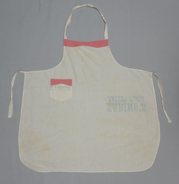 Bibbed apron with a small pocket made from bleached flour sacks. Parts of the bib and the pocket have been decorated with applied cotton cloth in pink (TRC 2017.3307).
