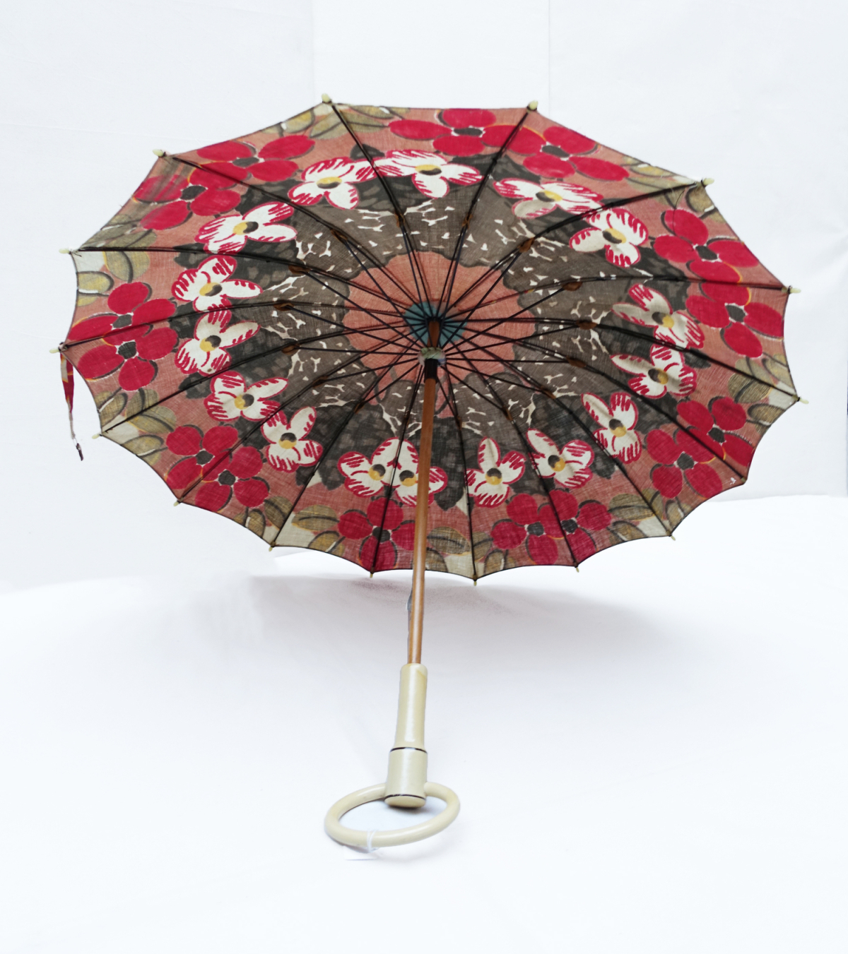 Parasol with a cloth cover decorated with printed, abstract flowers in red, green, white and yellow on a brown ground. Indonesia, 1920s.