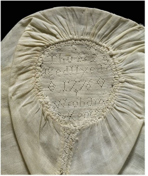 A late 18th century linen child&rsquo;s cap decorated with a band of hollie point