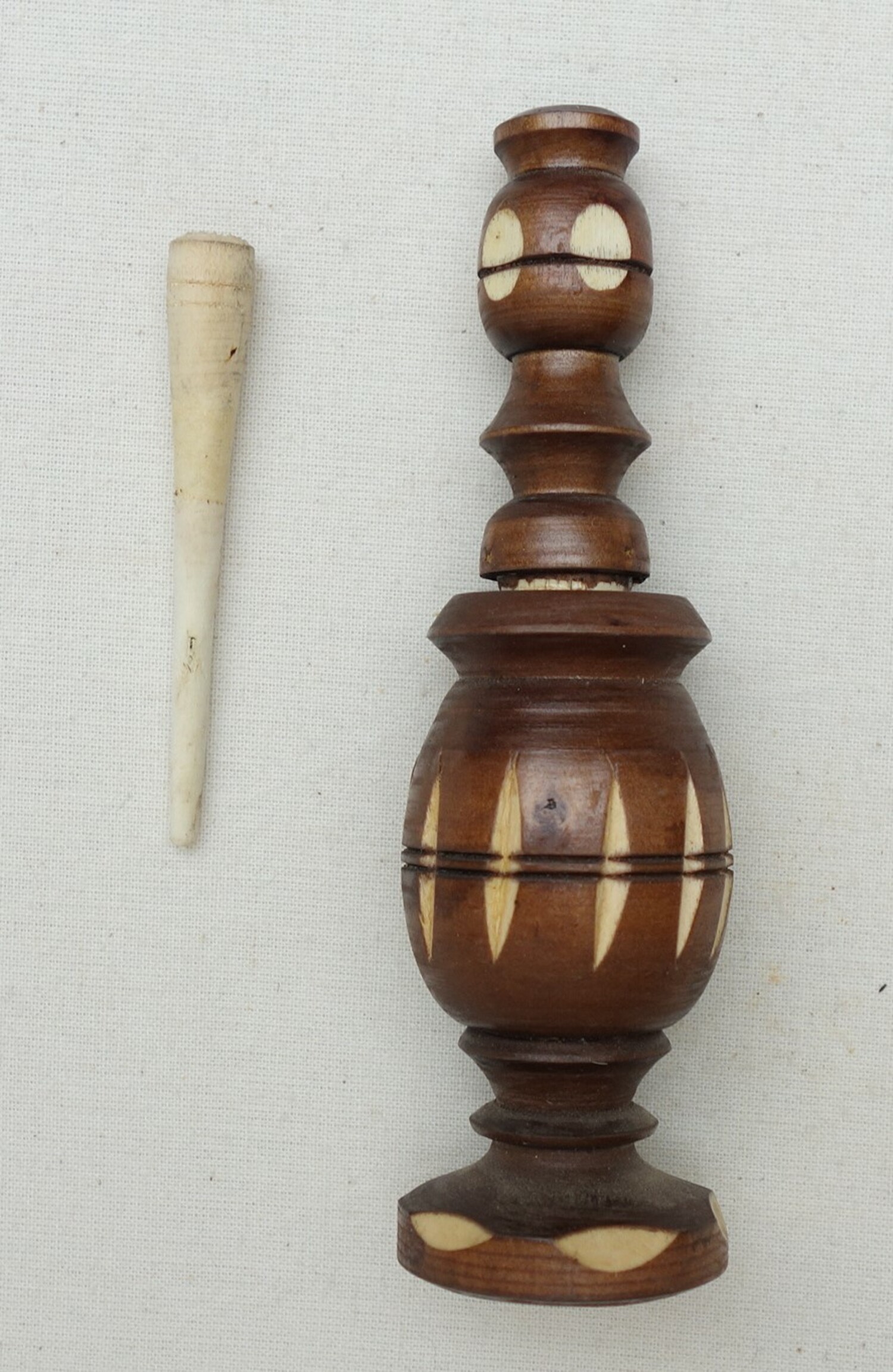 Fig. 2. Kohl container made of white wood that is stained dark brown, with a carved design of elongated ovals. Early 21st century. Meknes, Morocco (TRC 2001.0231a b).