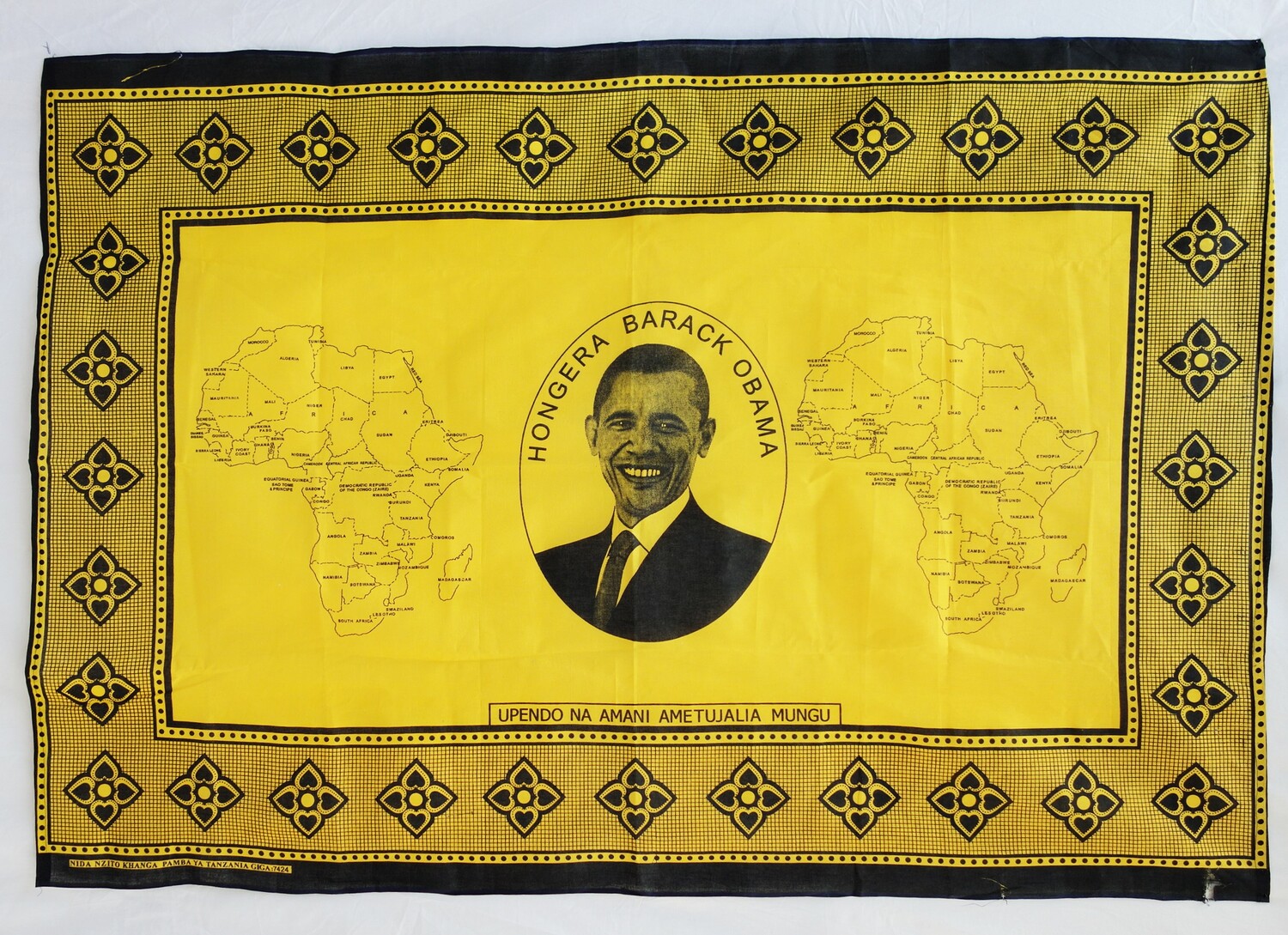 Kanga cloth from Tanzania, 2009, celebrating the US presidency of Barak Obama (TRC 2015.0350). The saying states: UPENDO NA AMANI AMETUJALIA MUNGU. "God has given us love and peace."