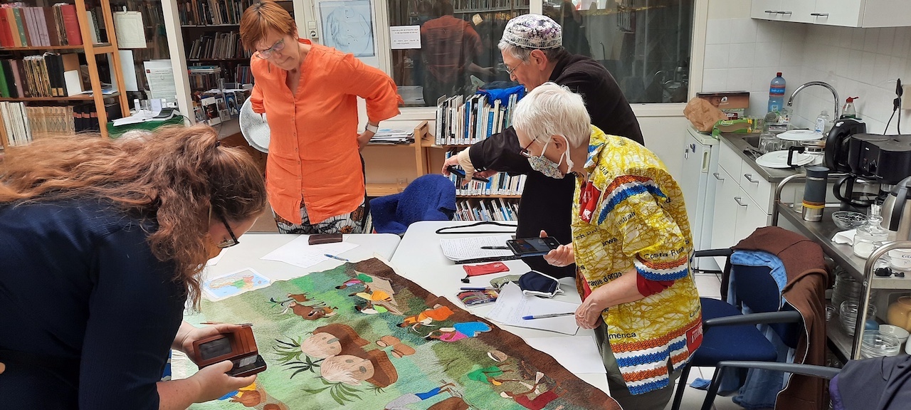 Participants of the study day on sub-Saharan embroidery look at a pictorial panel produced by the Sabane Kabuye workshop in Rwanda (TRC 2021.0500a). Photograph by Augusta de Gunzbourg.