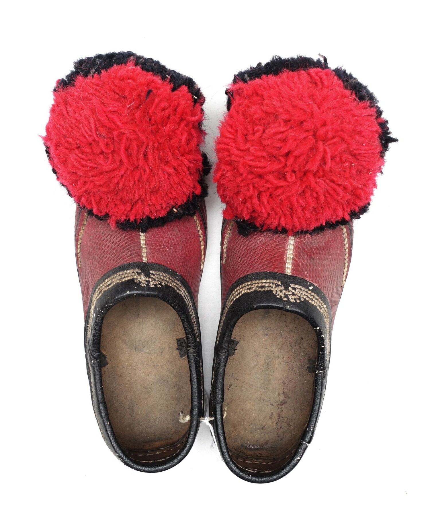 Pair of red and black leather shoes with white embroidered details, as well as two very large red and black pompoms at the toes. Albania, late 20th century (TRC 2022.1828a-b).