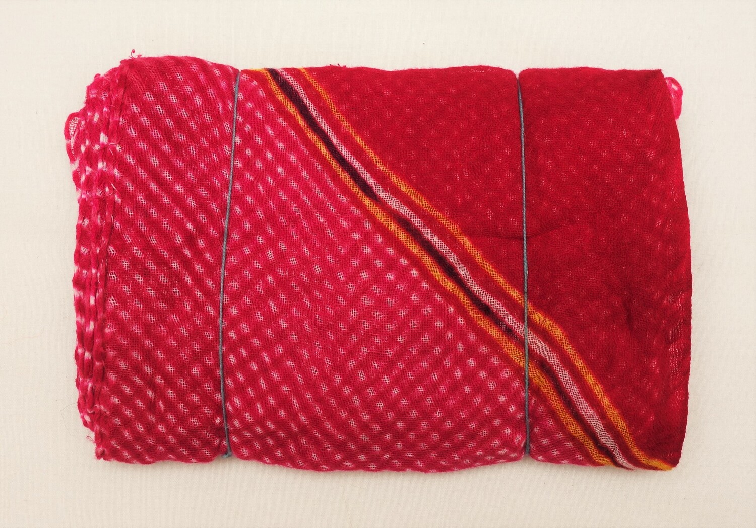 Bundle of folded, loosely woven cloth for a turban, which has been tied at regular intervals prior to dyeing. Mothra cloth. Jaipur, Rajasthan, India, 1980 (TRC 2022.2122).