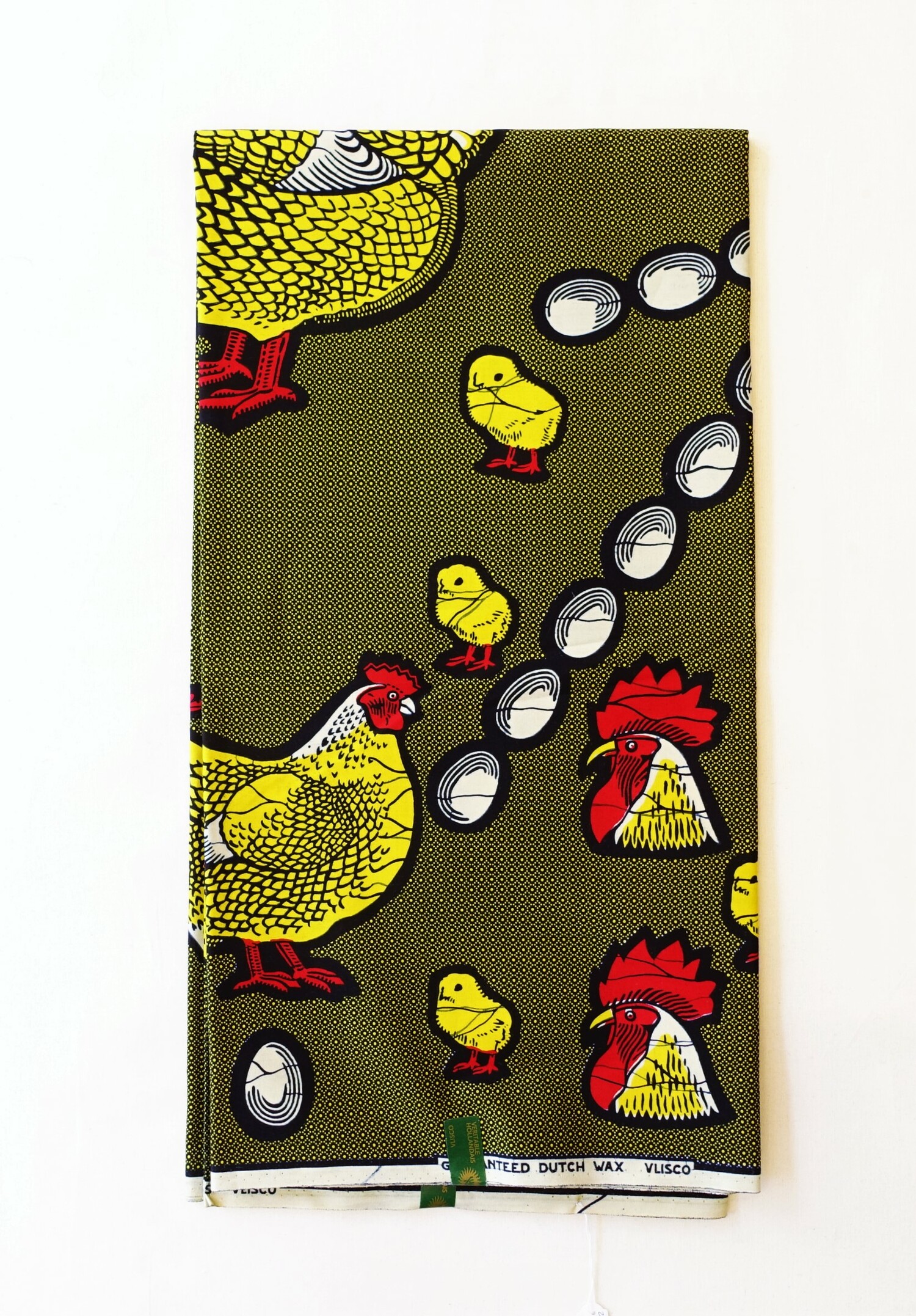 Length of cloth with an allover pattern of hens, cockerels, chicks and eggs. There are selvedge texts that state: "VERITABLE WAX HOLLANDAIS VLISCO" and "H628"., as well as printed Vlisco labels stuck on the cloth. The Netherlands, 2022 (TRC 2022.2365).