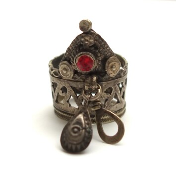 Silver ring with a wide decorated band with two rows of floral cut-outs, with two oval pendants under a crown decorated with a red glass circle, granulation and circular plates. Afghanistan, 20th century (TRC 2024.0800).