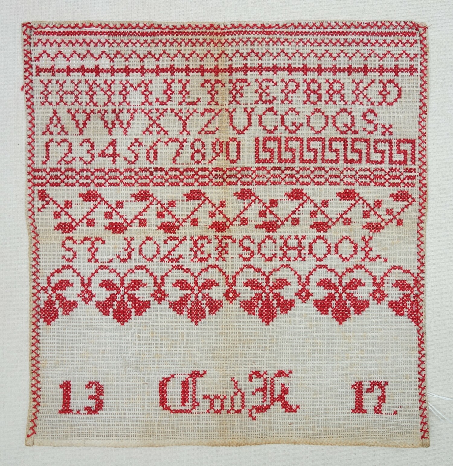 Fig. 5: Sampler with rows of geometric patterns, an alphabet, numbers, as well as: "ST. JOZEFSCHOOL   1.3 C vd K  17.", all in a red thread. Made by Cato van der Kleij in 1918 (TRC 2024.1725.01).