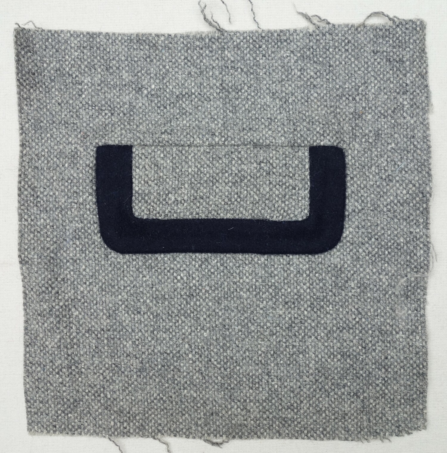 Sample of  grey mottled cloth with an inset pocket and flap. The Netherlands, 1930s (TRC 2024.1864).