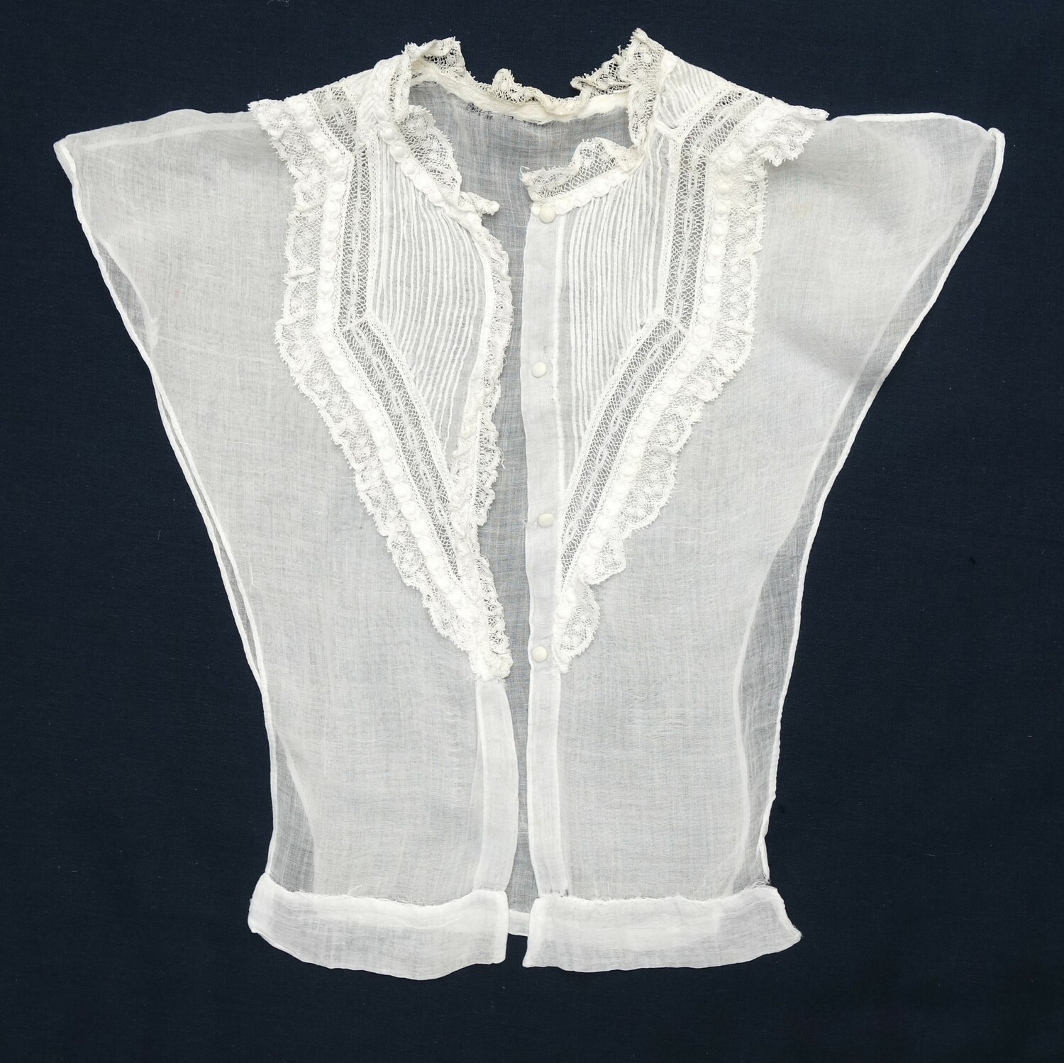 A white chemisette decorated with lace, embroidered bands and pin tucks. Europe, mid-19th century (TRC 2024.2497).