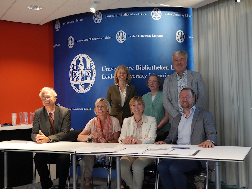 Official hand-over by the Ottow family of documents and textiles to the University Libraries and the TRC: Sitting behind the table: Prof. Annetje Ottow (Chair, Leiden University Board, second from the left), and her husband (to the far left), sister (right), and brother (far right). Standing behind them, from left to right: Dr Alette Stas-Bax (Chair Leids Universiteitsfonds), Dr Gillian Vogelsang-Eastwood (Director Textile Research Centre), and Dr Kurt De Belder (Director Leiden University Libraries). Photograph by Guus Janssen, Leiden University Libraries.